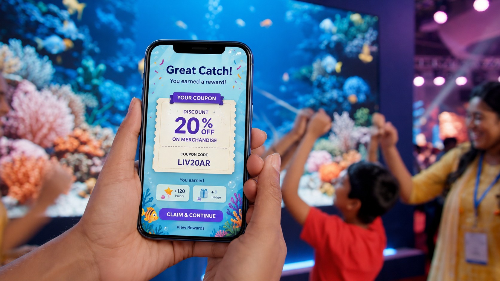 Guest holds a smartphone showing a Great Catch reward screen — 20% off brand coupon — with the underwater aquarium wall and a family celebrating in the background
